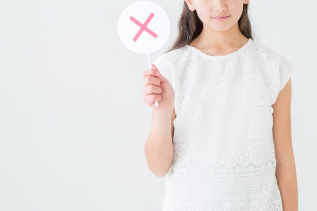 バツの札を持つ女性