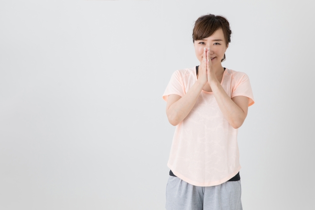 ごめんねのポーズをとる女性