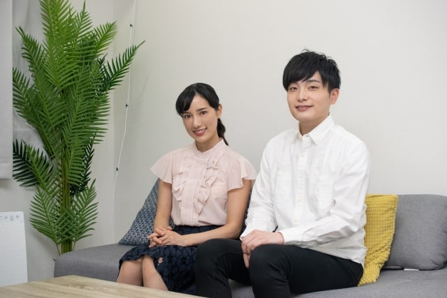 ソファで姿勢を正す同棲中のカップル