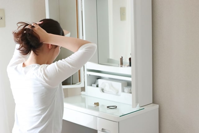 化粧台の前で身支度をする女性