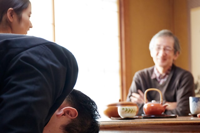 結婚挨拶でお辞儀をする男性と見つめる両親