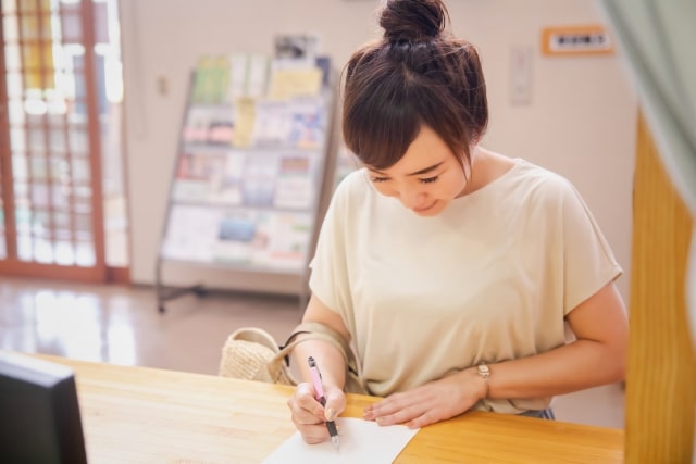 窓口で書類に記入する女性