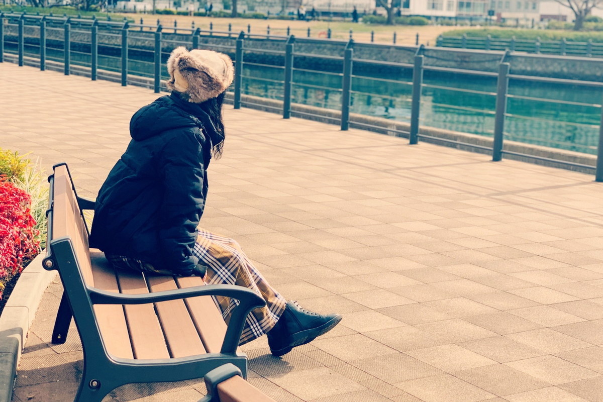 ひとりでベンチに座る女性