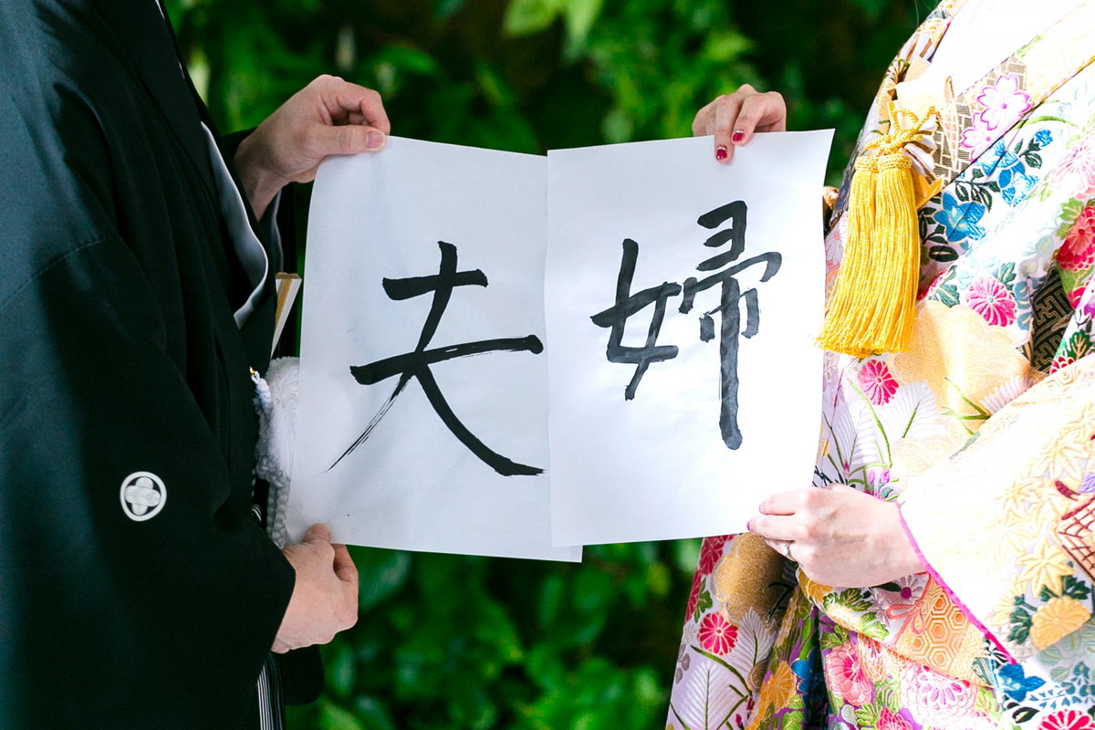 夫婦と書いた紙を持つ新婚カップル